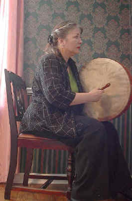 sitting, holding the bodhran facing the other way